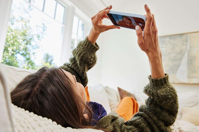 Mujer recostada que mira su teléfono móvil